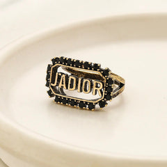 Anillo abierto con letras incrustadas en negro