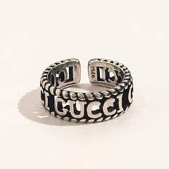 Anillo abierto con letras grabadas y bordes de cuerda