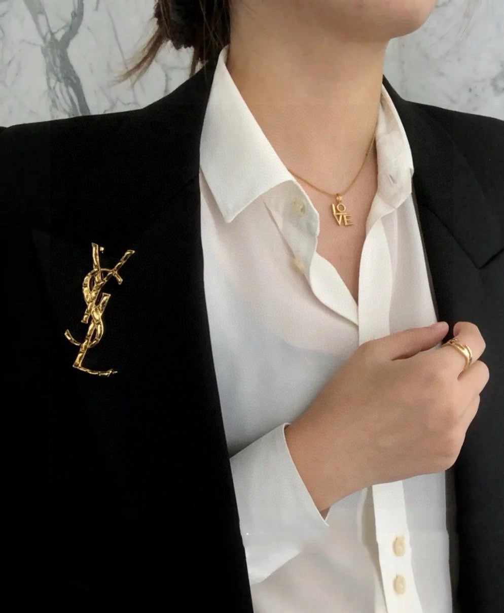 Broche de letra contorneada con incrustación oscura