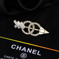 Broche de flecha y emblema con detalles en piedra