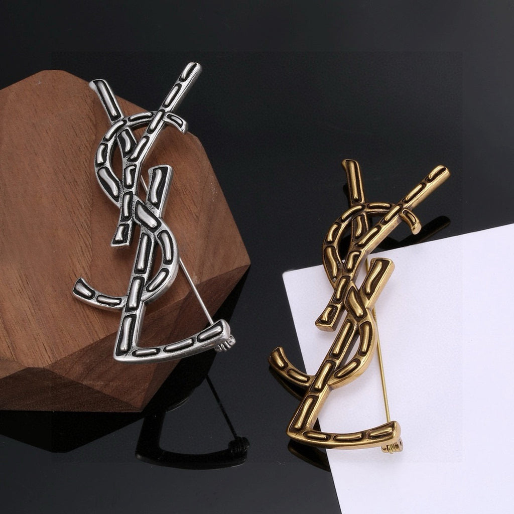 Broche de letra contorneada con incrustación oscura