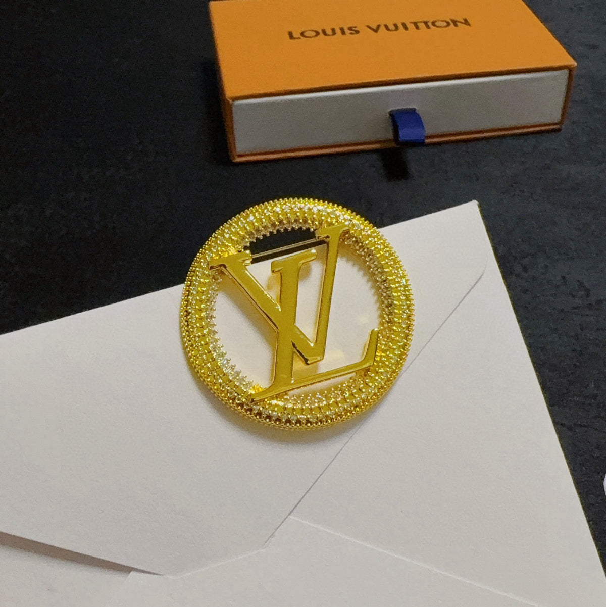 Broche con emblema de letra redonda y borde de cuerda