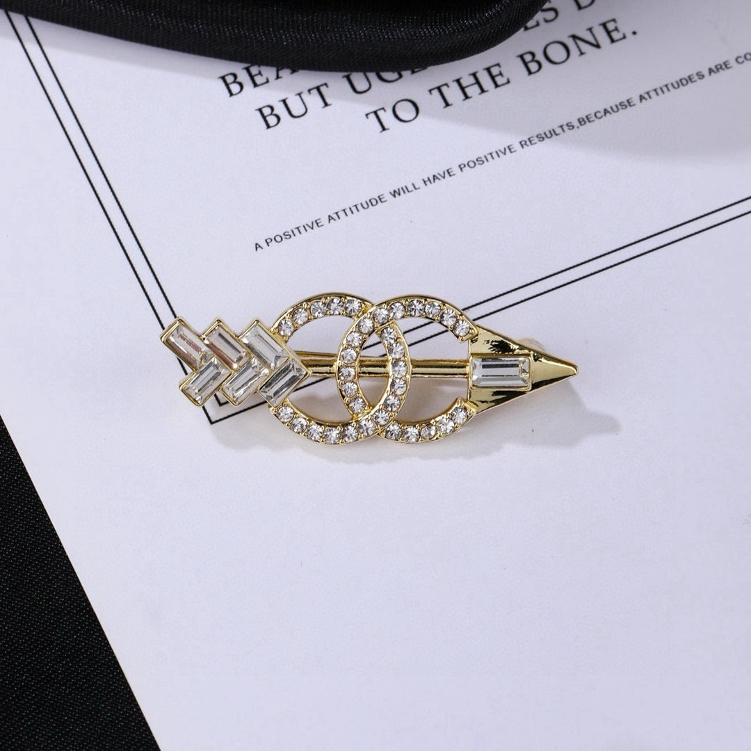 Broche de flecha y emblema con detalles en piedra