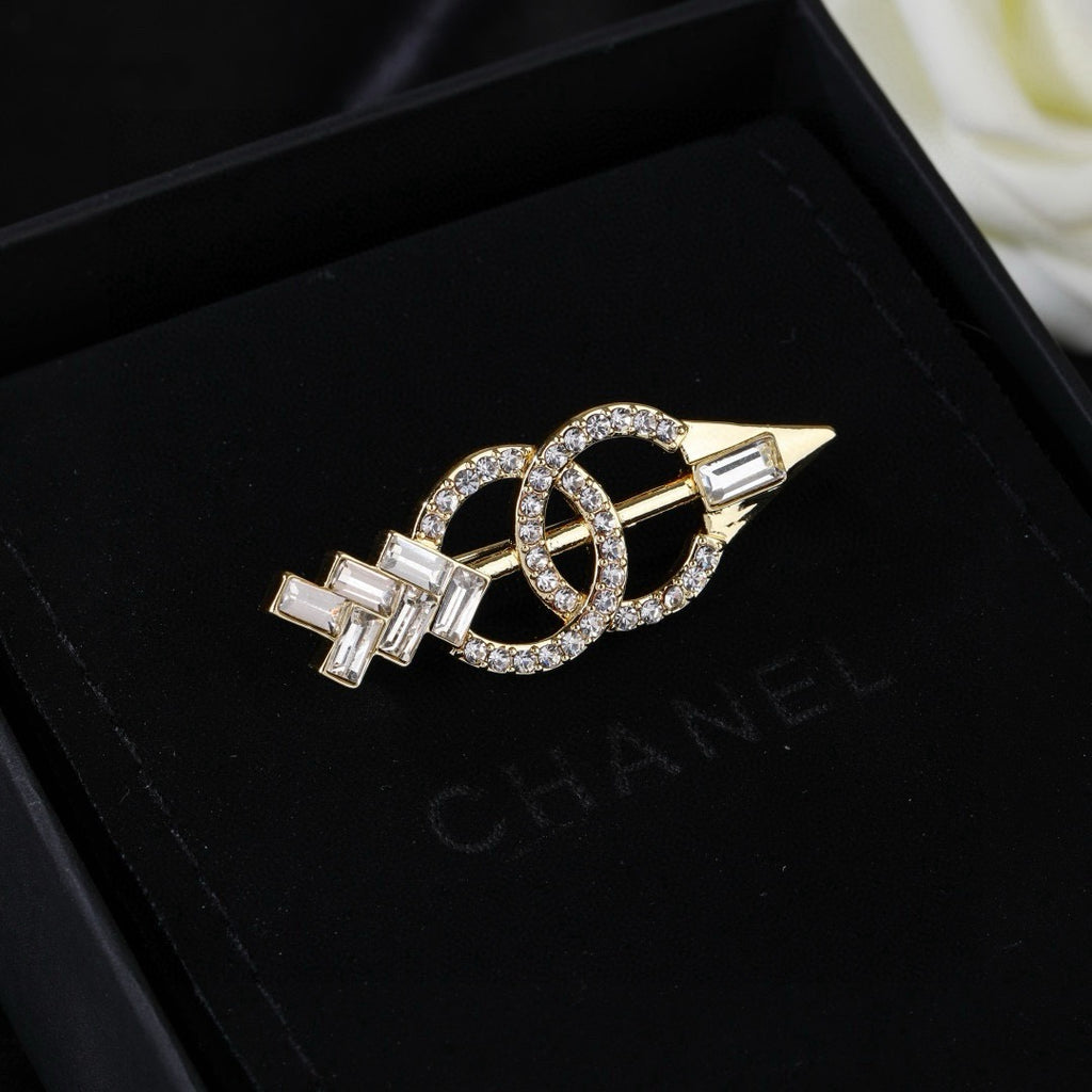 Broche de flecha y emblema con detalles en piedra