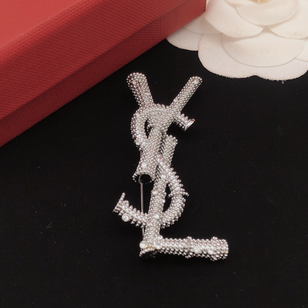 Broche de letra de cuerda trenzada con detalles de piedra