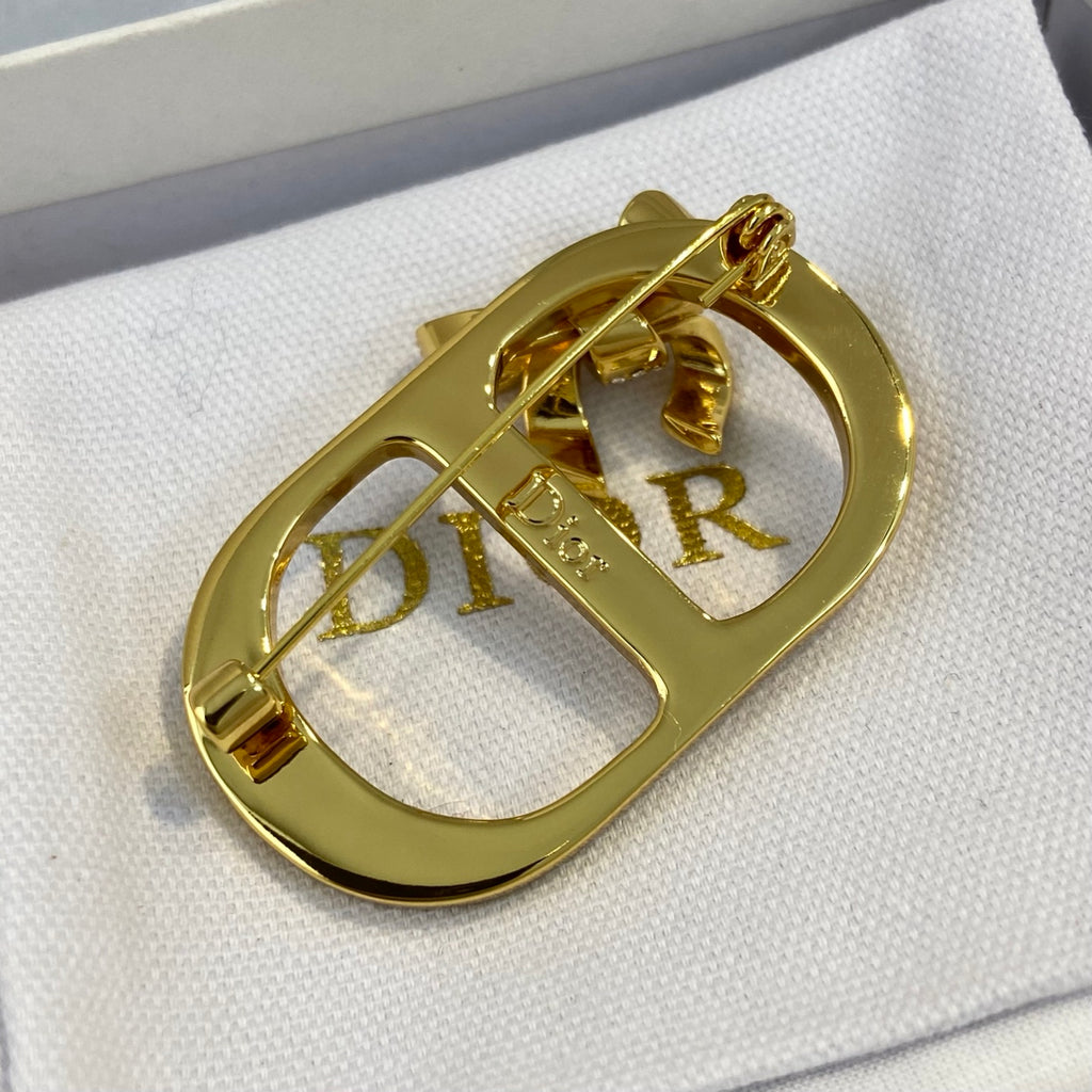 Broche con marco de lazo y letra con detalles de piedras