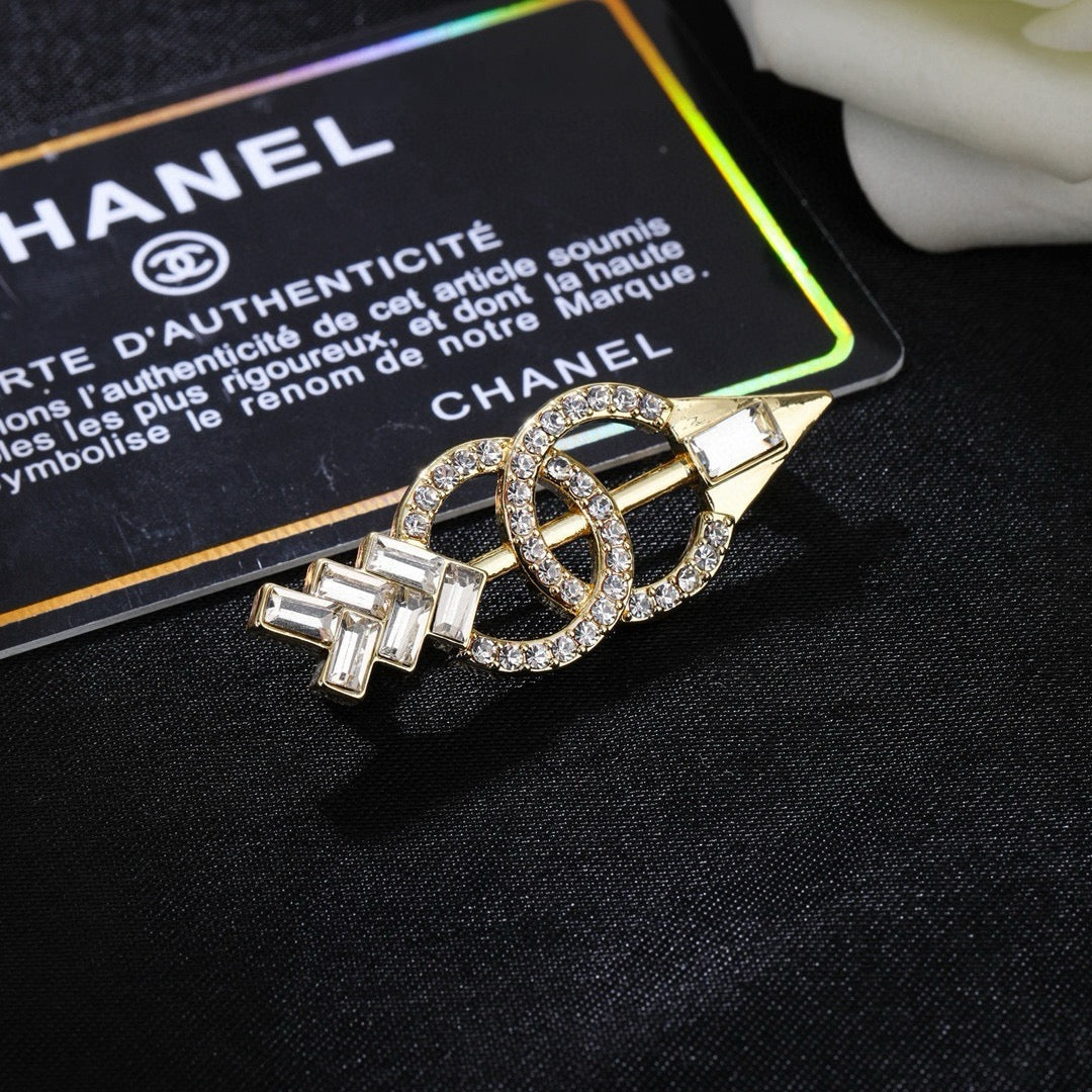 Broche de flecha y emblema con detalles en piedra