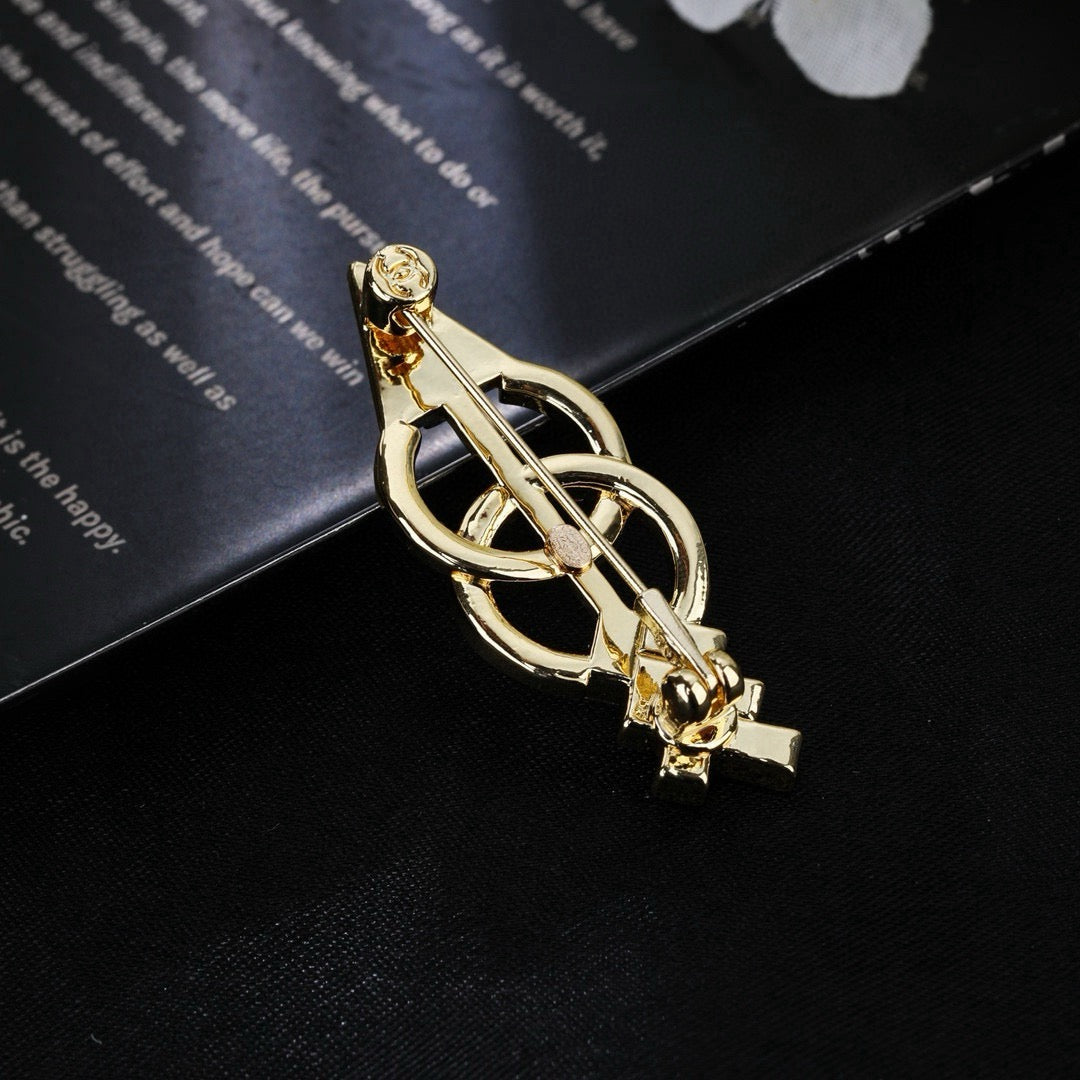 Broche de flecha y emblema con detalles en piedra