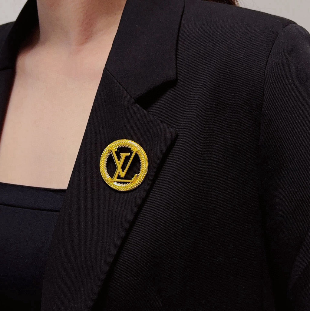 Broche con emblema de letra redonda y borde de cuerda