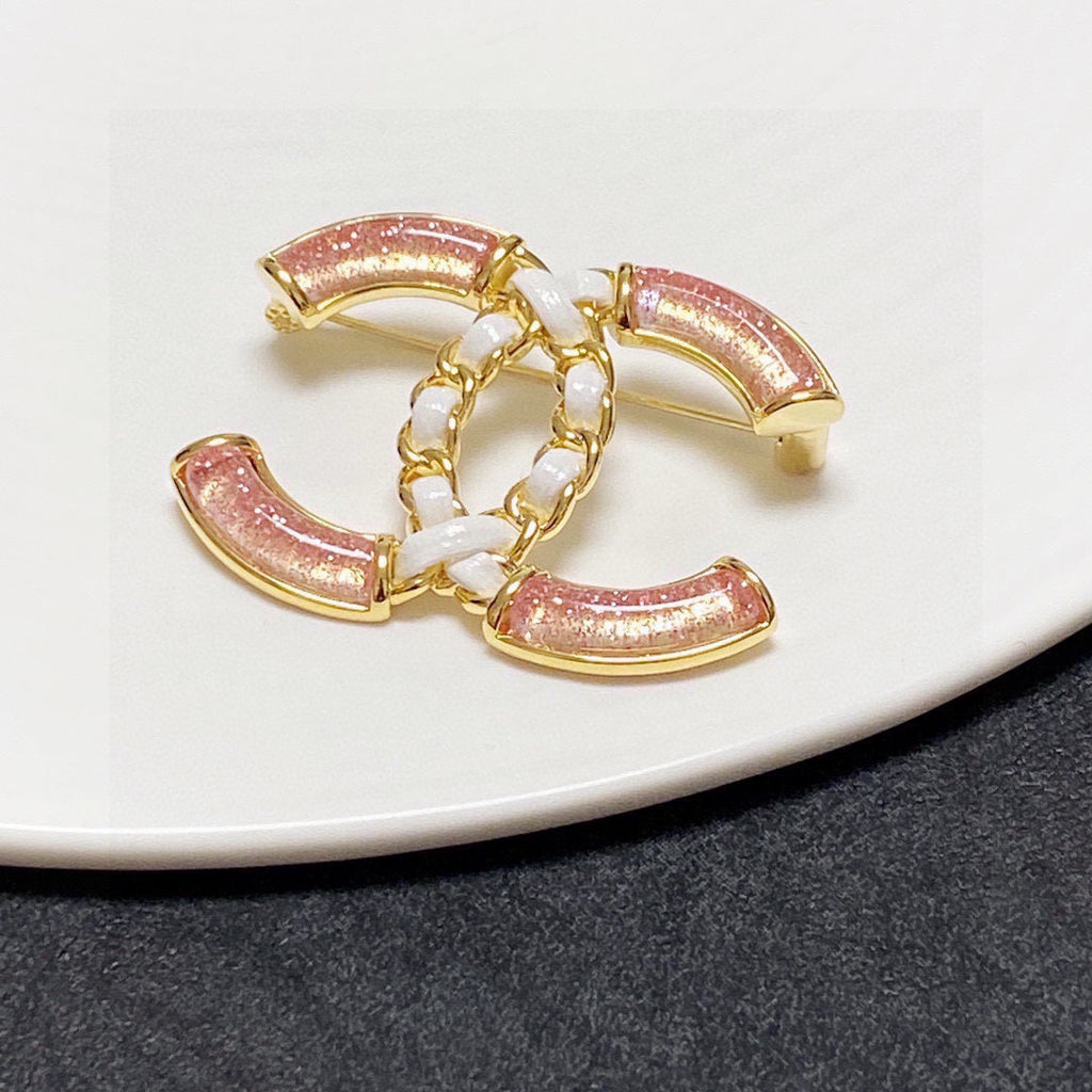 Broche de emblema con piedra rosa y eslabones trenzados