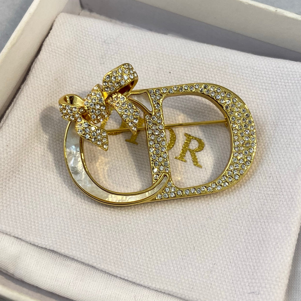 Broche con marco de lazo y letra con detalles de piedras