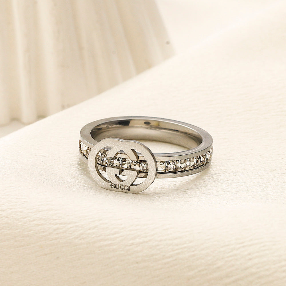 Anillo de banda con emblema fino y detalles en piedra