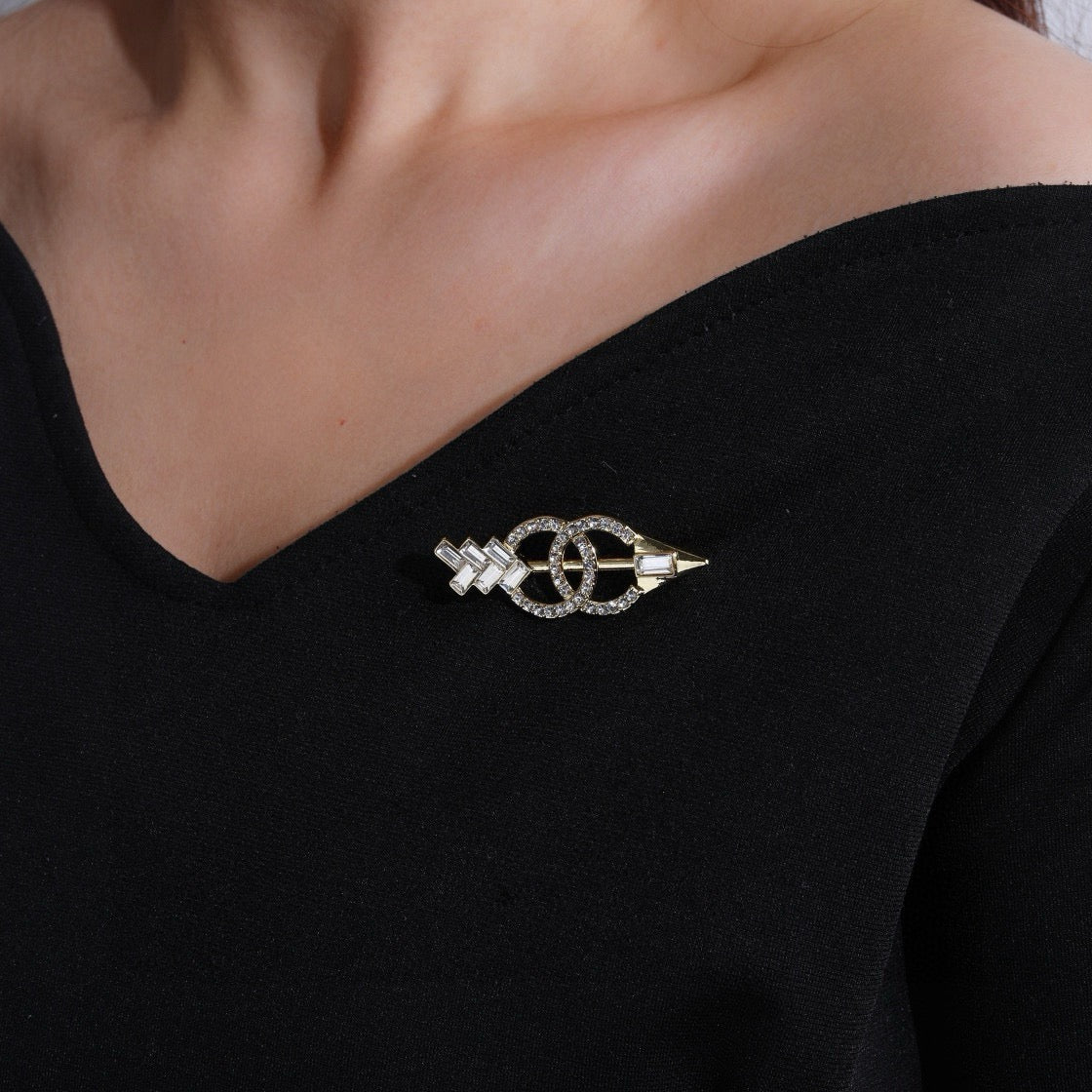 Broche de flecha y emblema con detalles en piedra