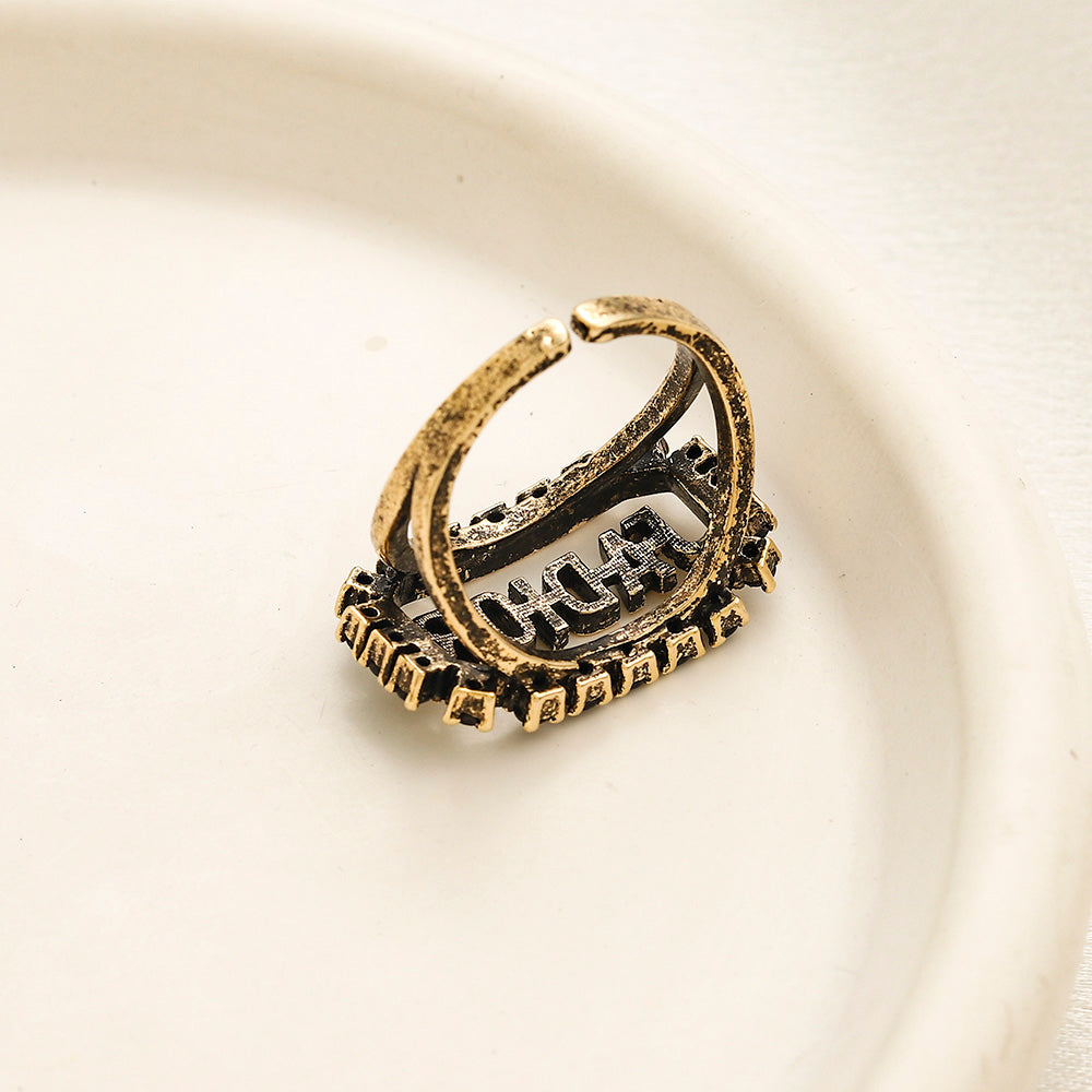 Anillo abierto con letras incrustadas en negro
