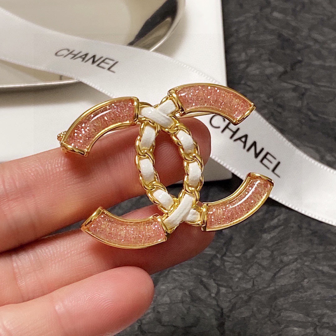 Broche de emblema con piedra rosa y eslabones trenzados