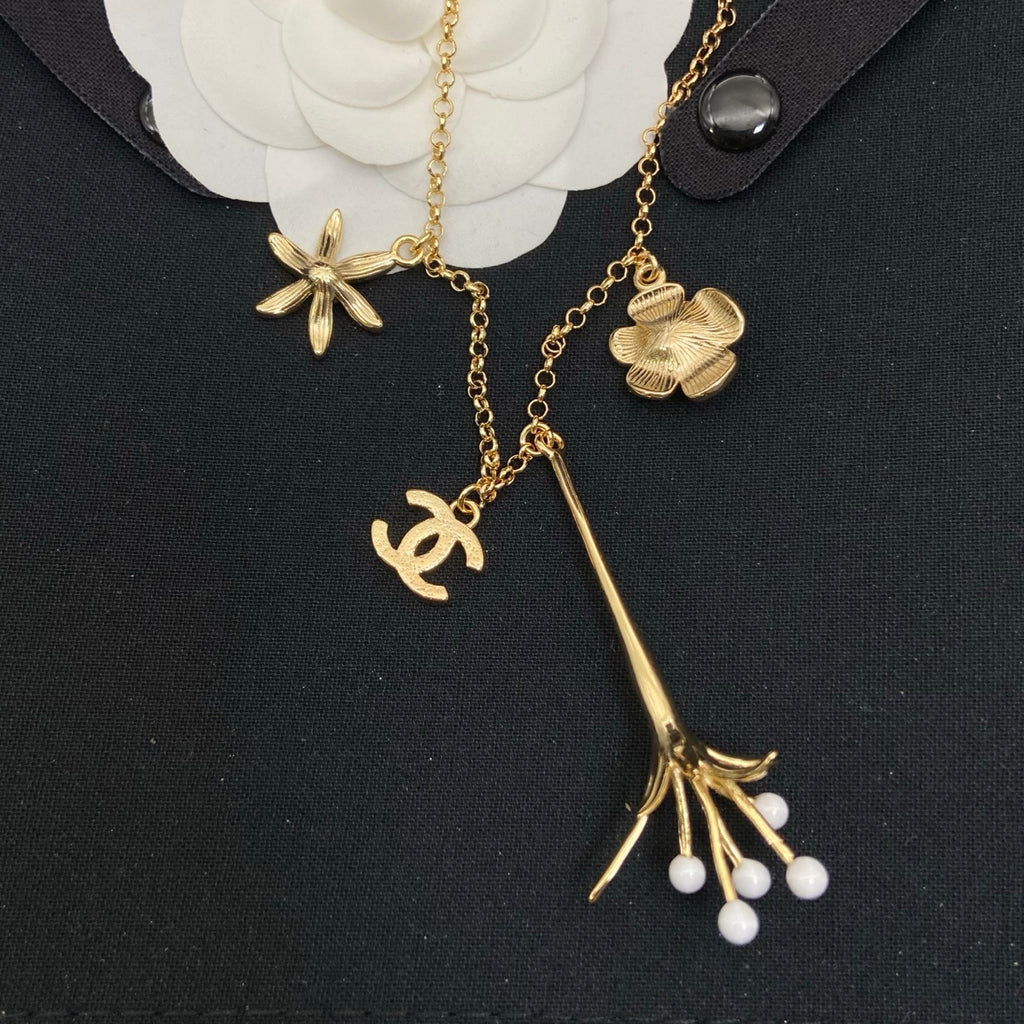 Collar tipo choker con dije floral esmaltado en tono dorado y detalles de perlas