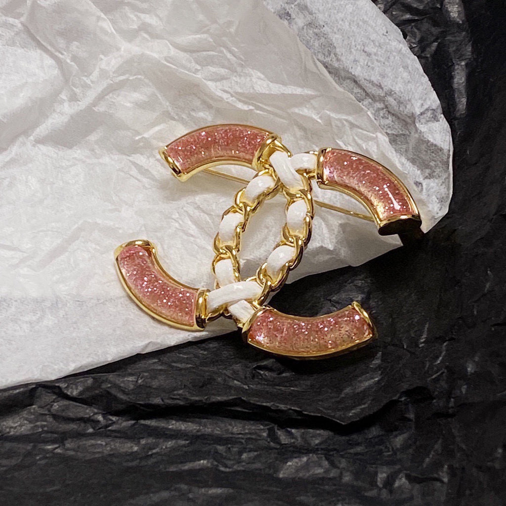 Broche de emblema con piedra rosa y eslabones trenzados