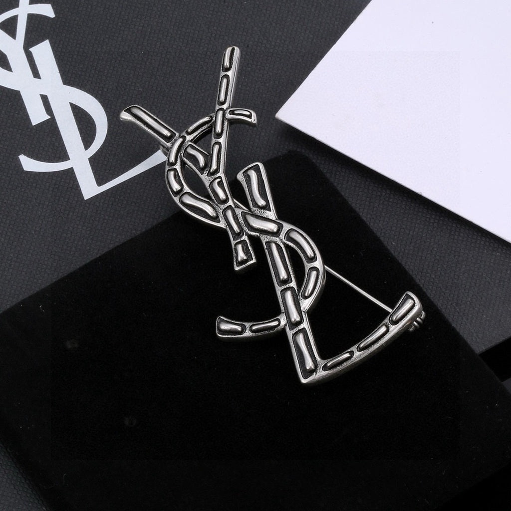Broche de letra contorneada con incrustación oscura