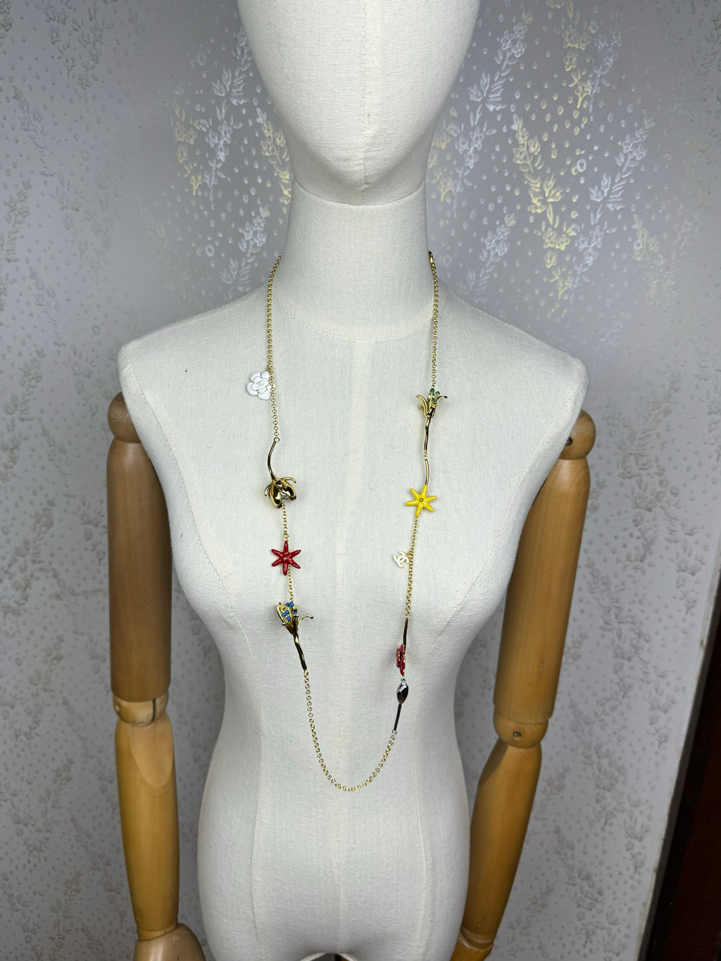 Colar comprido em tom dourado com pendente de flores em esmalte multicolorido