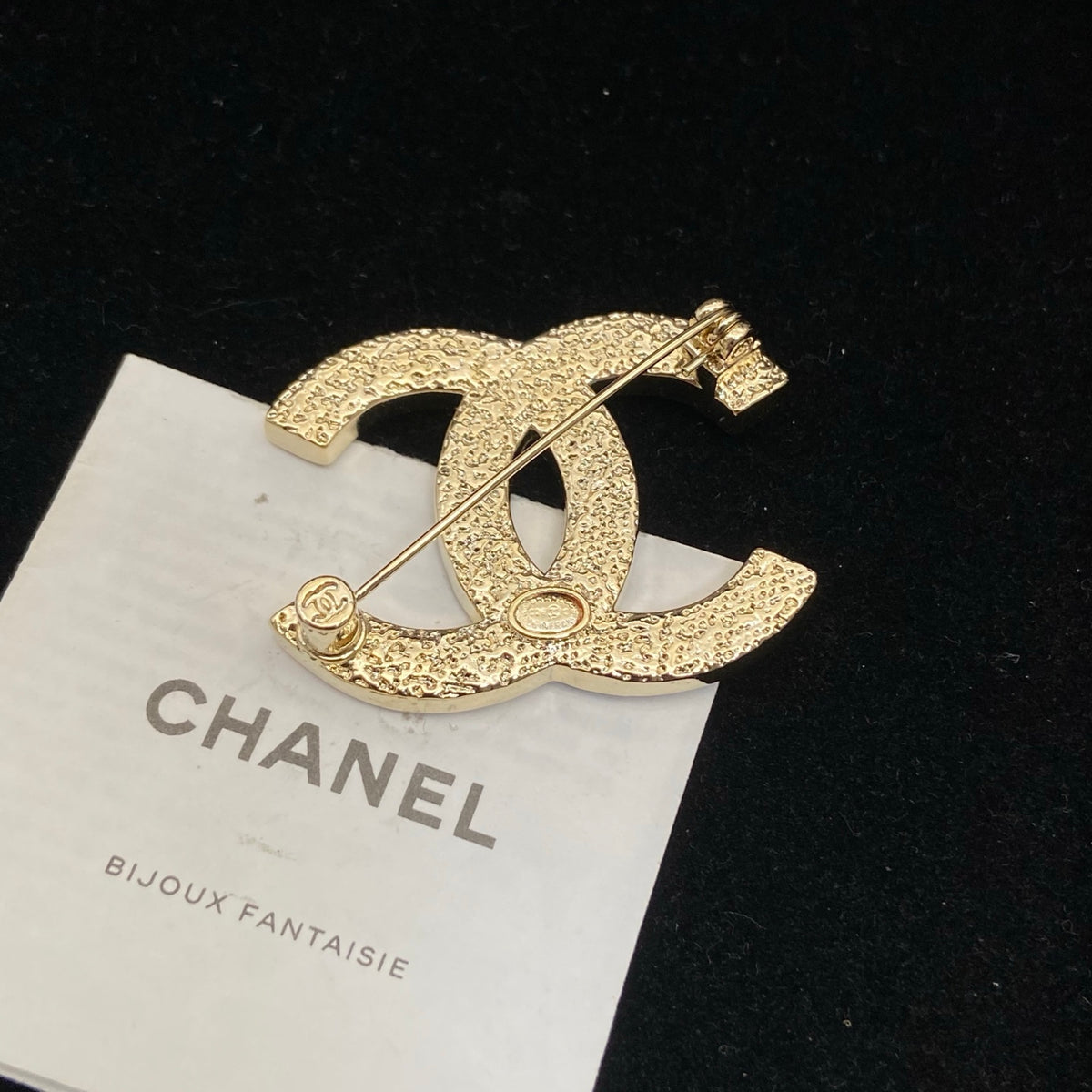 Broche delgado con emblema entrelazado engastado en piedra