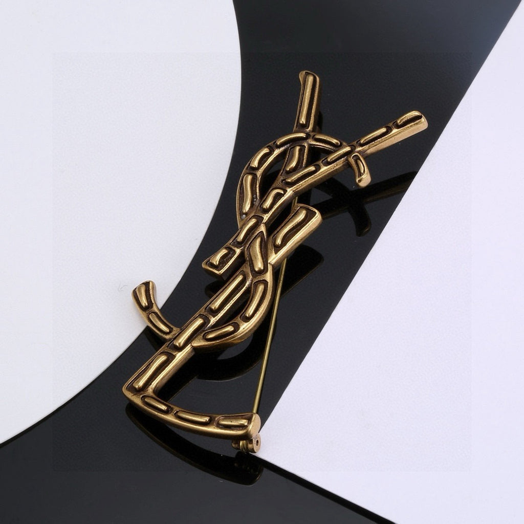 Broche de letra contorneada con incrustación oscura