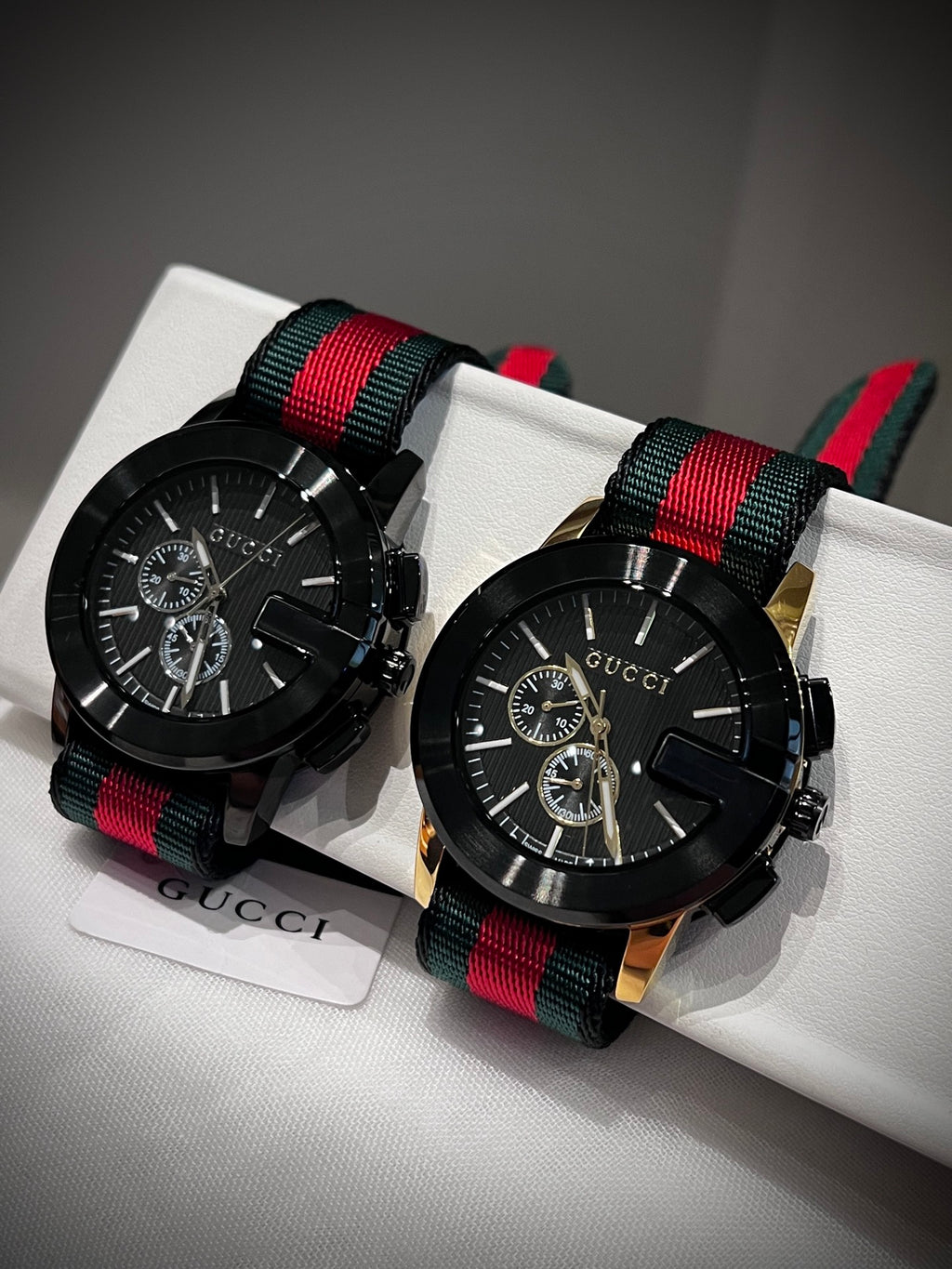 Black multi-dial watch with red and green striped strap