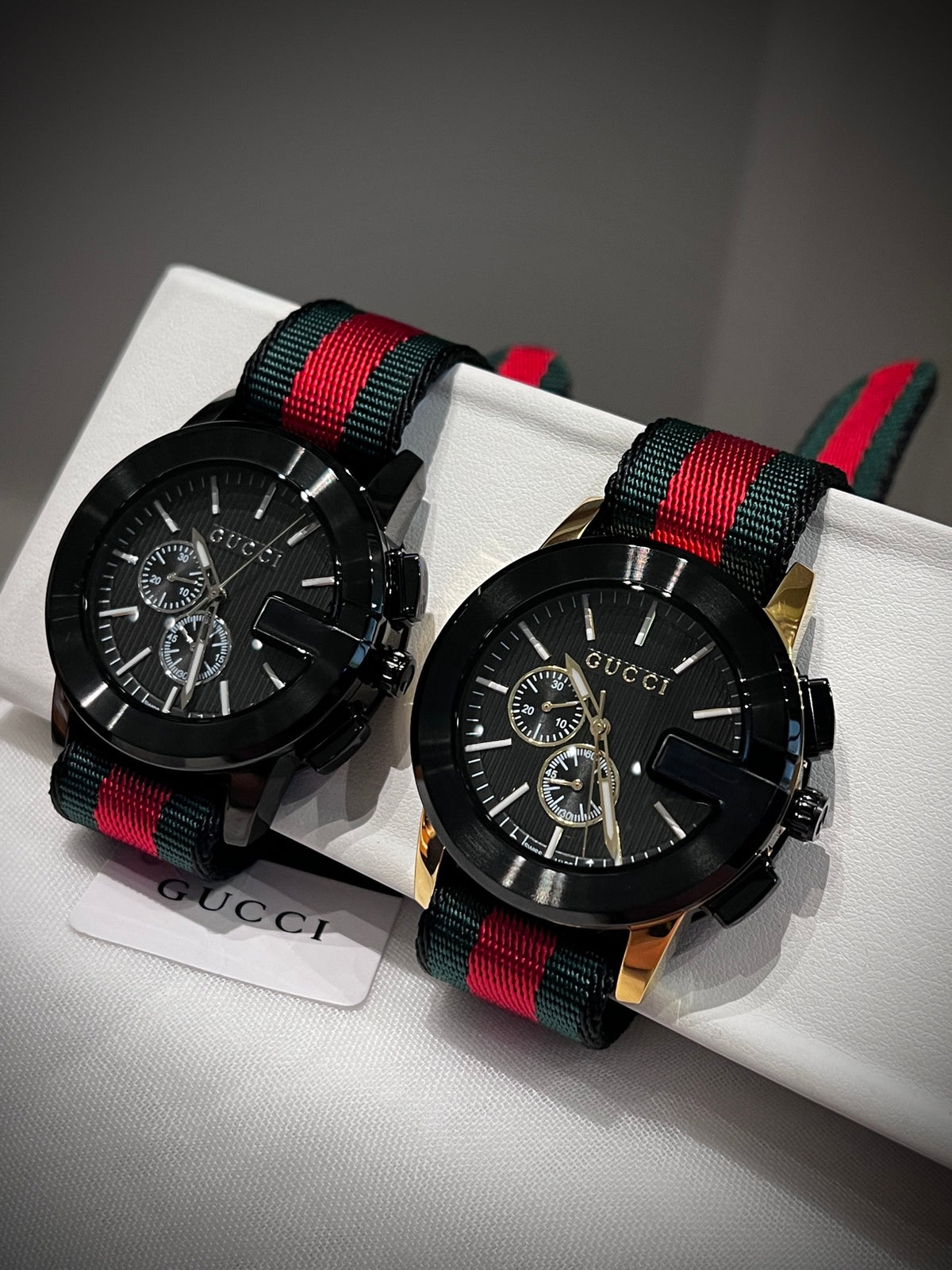 Black multi-dial watch with red and green striped strap