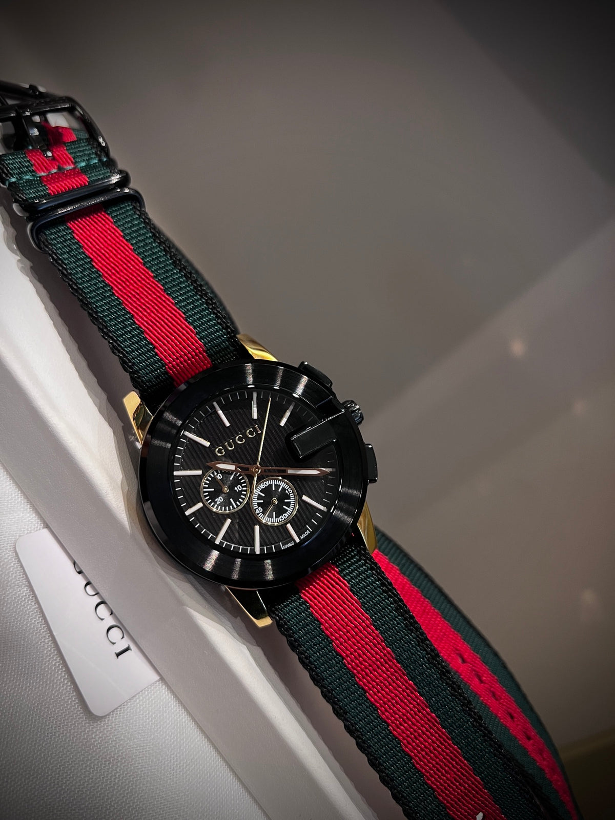 Black multi-dial watch with red and green striped strap