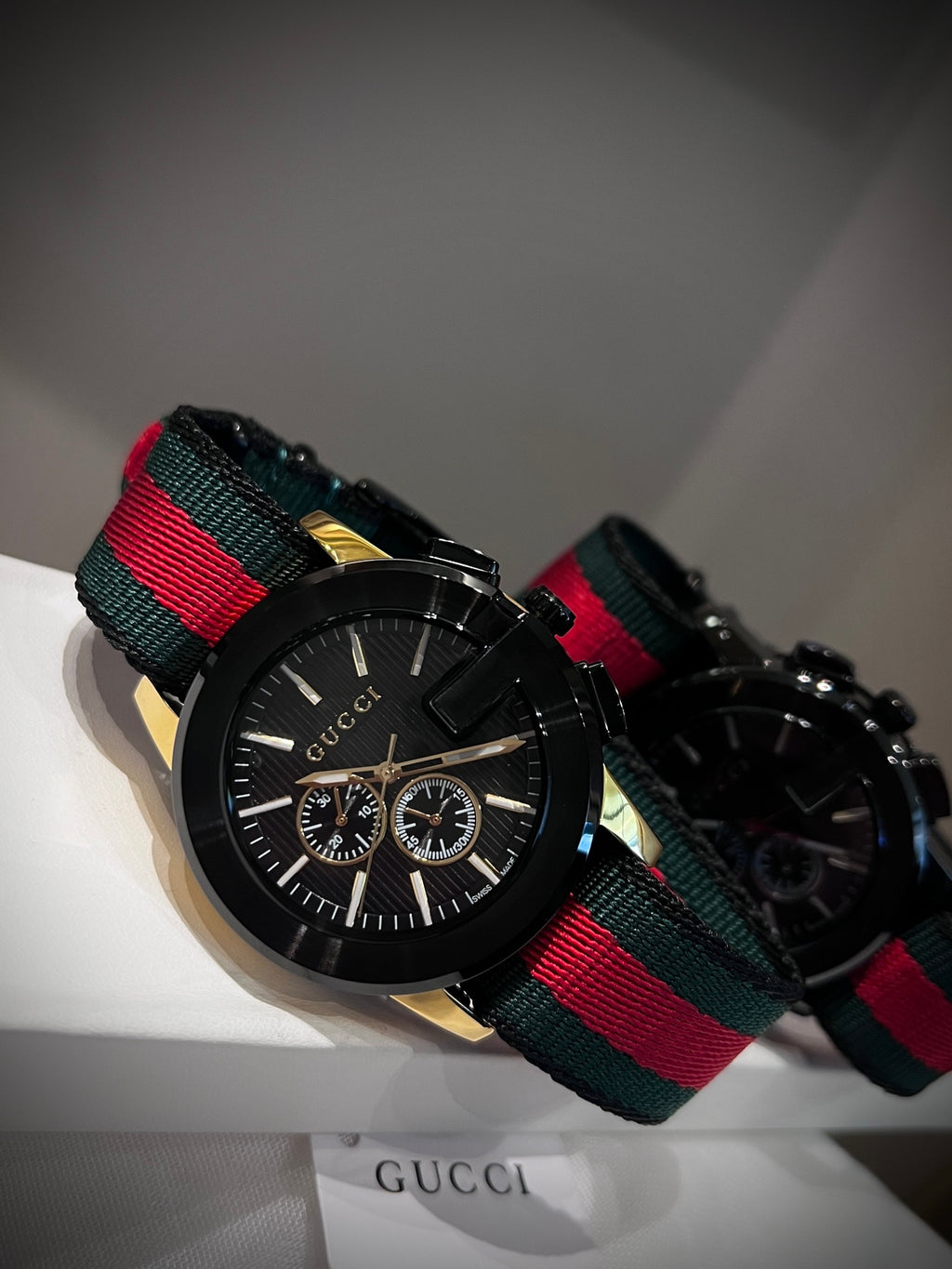 Black multi-dial watch with red and green striped strap