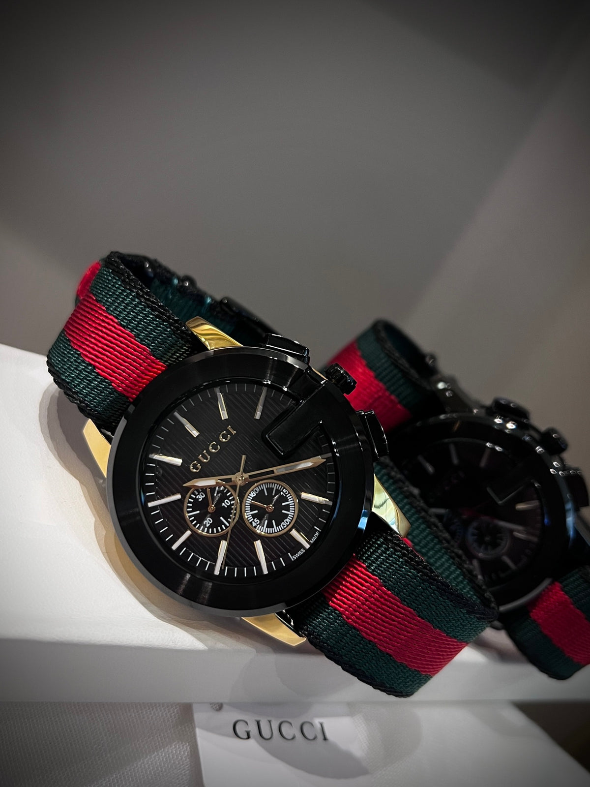 Black multi-dial watch with red and green striped strap