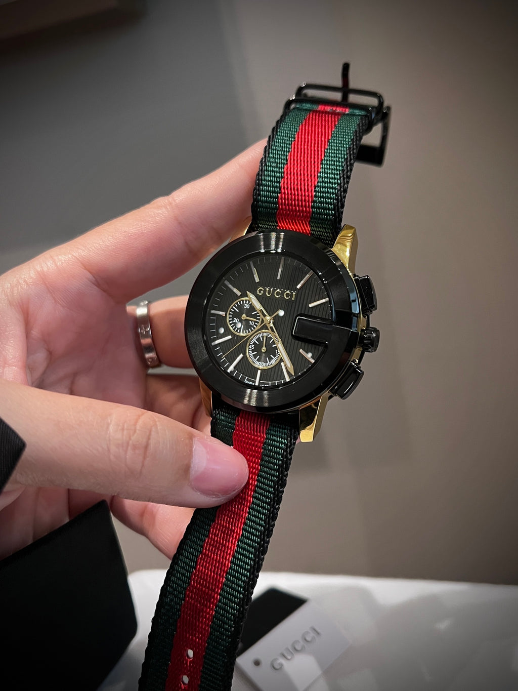 Black multi-dial watch with red and green striped strap