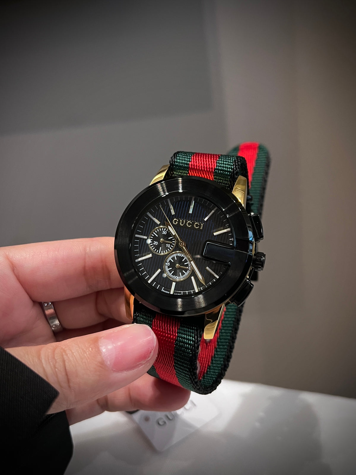 Black multi-dial watch with red and green striped strap