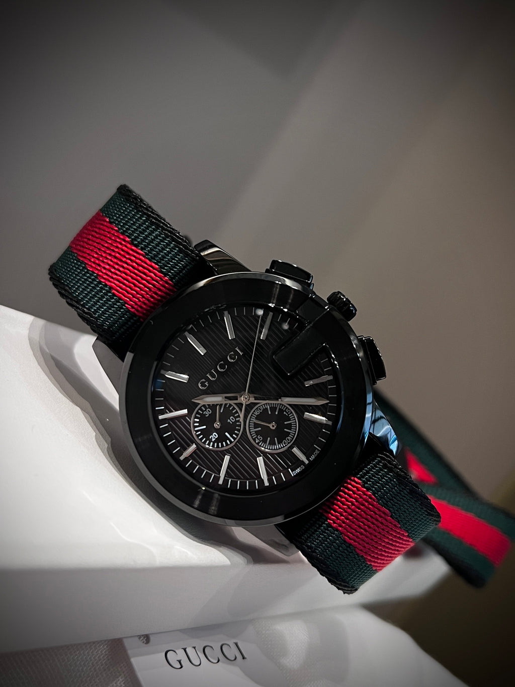 Black multi-dial watch with red and green striped strap