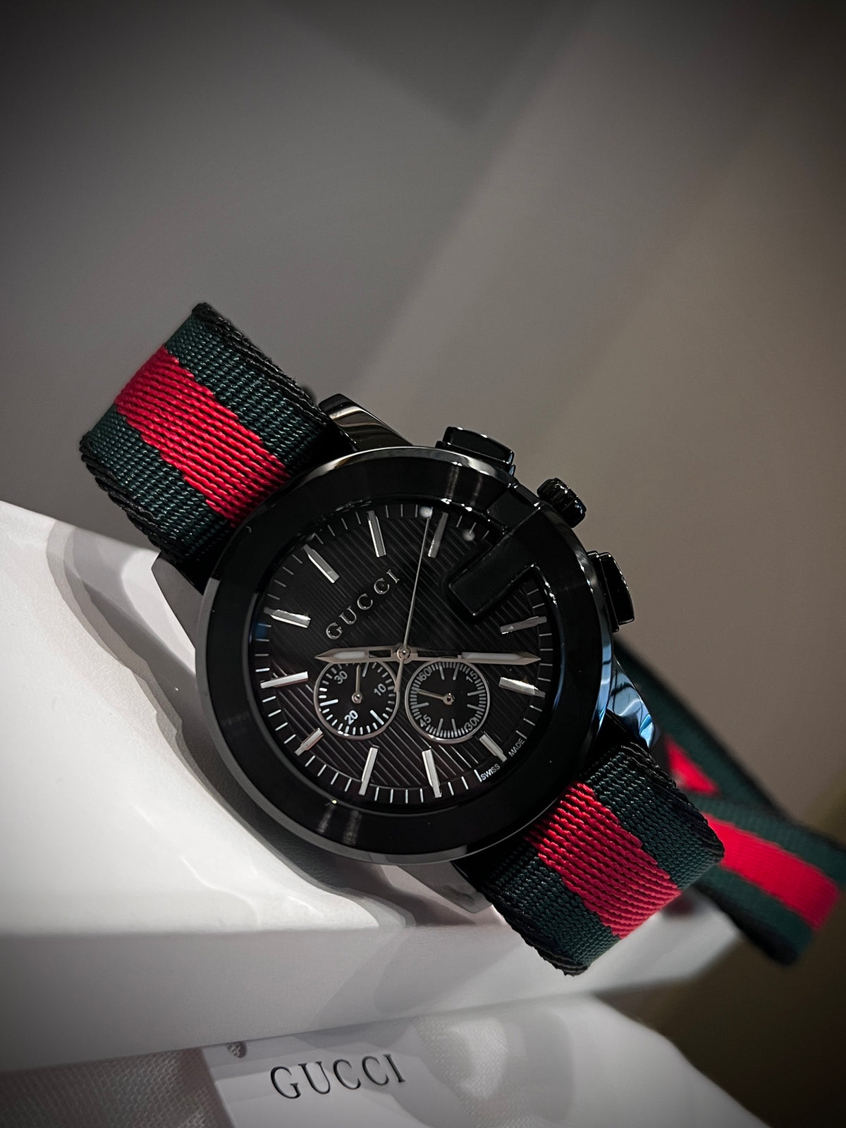 Black multi-dial watch with red and green striped strap