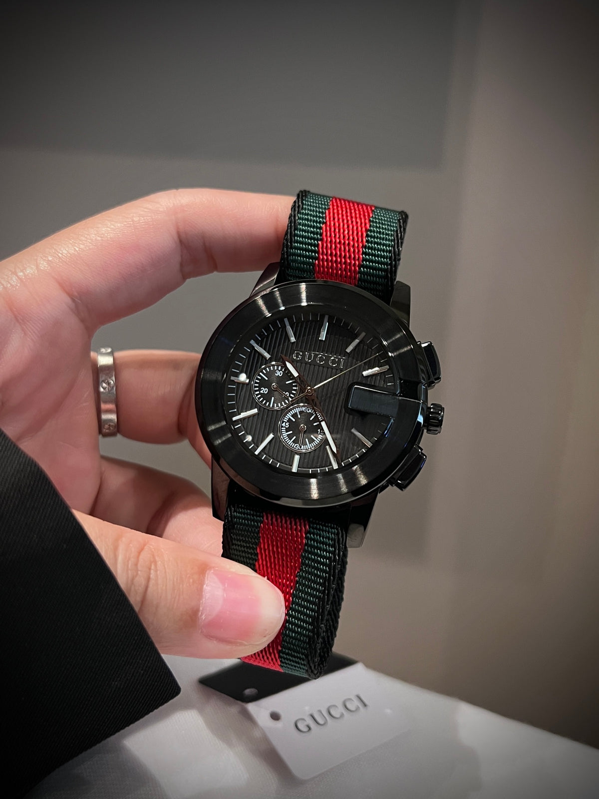 Black multi-dial watch with red and green striped strap